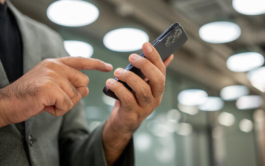 Young man holding using smartphone on urban city background.