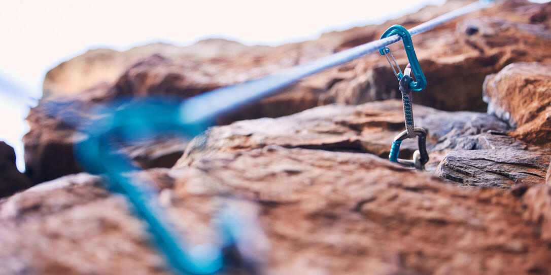 Rock climbing, mountain and closeup of rope and hook for adventure, freedom and extreme sports in nature. Fitness, hiking and carabiner, equipment or gear in stone for training, activity or challenge
