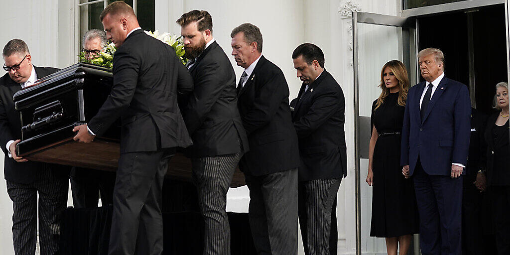 US-Präsident Donald Trump und First Lady Melania Trump stehen nebeneinander, während der Sarg von Robert Trump nach einer Gedenkfeier im Weißen Haus in einen Leichenwagen geladen wird. Foto: Evan Vucci/AP/dpa