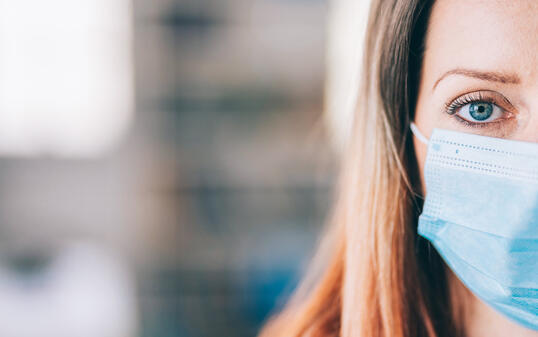 Woman wearing protective face mask in the office for safety and protection during COVID-19