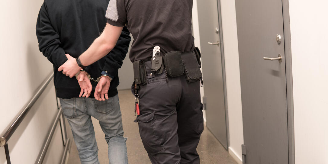 Prison guard esicort inmate throught corridor in jail corridor for booking.