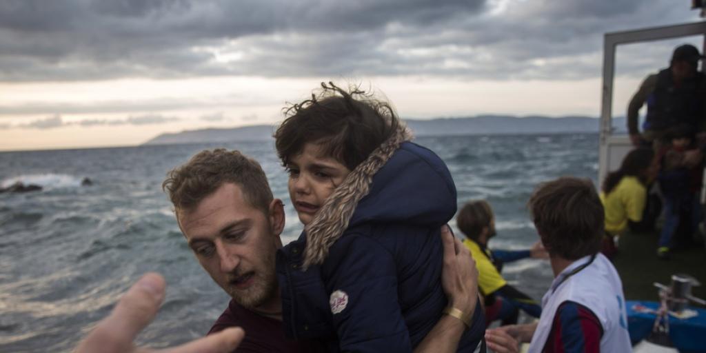 Ein Fotograf hilft auf der griechischen Insel Lesbos einem Mädchen an Land, nach dem es zusammen mit über 100 anderen Flüchtlingen in einem Boot von der türkischen Küste über das Mittelmeer gekommen war (Archiv)