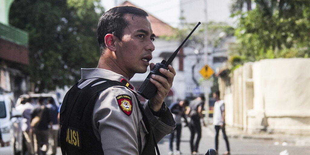 Ein indonesischer Polizist sichert den Tatort ab. Bei dem Selbstmordanschlag in der Grossstadt Surabaya wurden erneut Kinder eingesetzt.