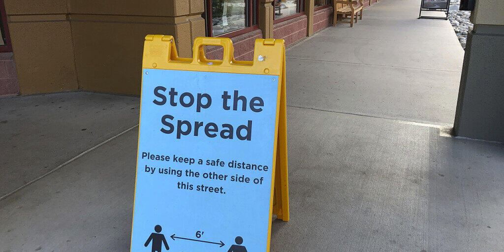 ARCHIV - Ein Schild vor einem Einkaufszentrum weist Kunden darauf hin, Abstand zu halten, um die Verbreitung des Coronavirus einzudämmen. Foto: David Zalubowski/AP/dpa