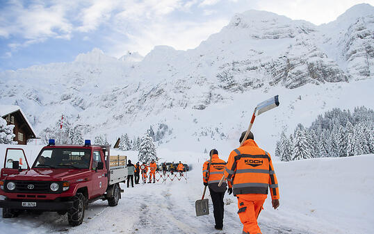 Männer mit Schaufeln passieren am Freitag eine Strassensperre auf der Passhöhe, nach einem Abgang einer 300 Meter breiten Lawine auf der Schwägalp AR. Nach derzeitigen Erkenntnissen wurden drei Personen leicht verletzt.