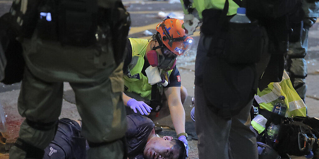 Wurde von Demonstranten in Hongkong attackiert: Medizinpersonal kümmert sich um einen verletzten Mann am Boden.