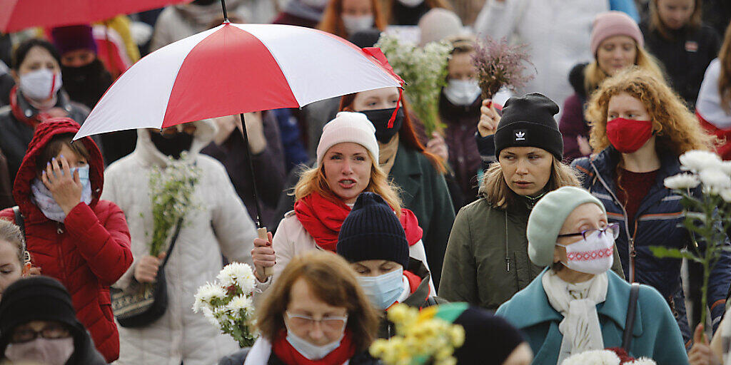 Belarussische Frauen mit Regenschirmen in den Farben der alten belarussischen Nationalflagge. Foto: -/AP/dpa