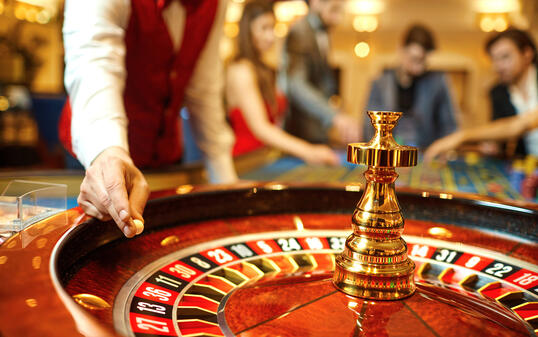 The croupier holds a roulette ball in a casino in his hand.