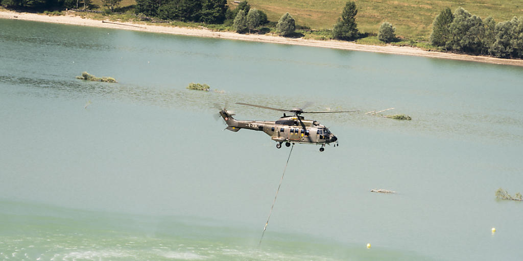 Ein Armeehelikopter entnimmt Wasser aus dem Greyerzersee, um damit Kühe in den Freiburger Voralpen zu tränken. (Archiv)