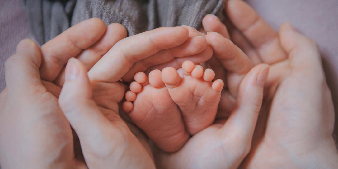 Mom's arms hug the baby. the legs of a newborn. the heels, the fingers of a baby, a child. Childbirth, maternity capital, artificial insemination, IVF, mortgage, family, love.
