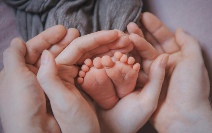 Mom's arms hug the baby. the legs of a newborn. the heels, the fingers of a baby, a child. Childbirth, maternity capital, artificial insemination, IVF, mortgage, family, love.