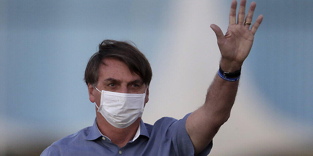 Jair Bolsonaro, Präsident von Brasilien, der mit Covid-19 infiziert ist, trägt eine Schutzmaske, während er an einer Zeremonie vor seinem Amtssitz teilnimmt. Foto: Eraldo Peres/AP/dpa