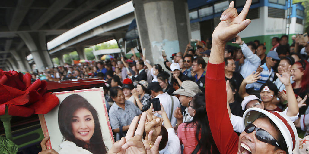 Unterstützer der früheren thailändischen Regierungschefin Yingluck Shinawatra halten bei einer Kundgebung in Bangkok ein Bild von ihr hoch. Yingluck soll nach Dubai geflohen sein. (Archiv)