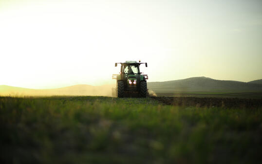 while the tractor in a field at sunset