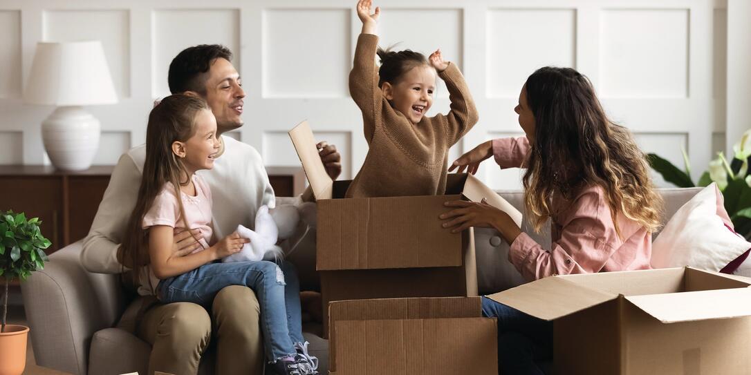 Happy parents and children playing on moving day unpacking boxes