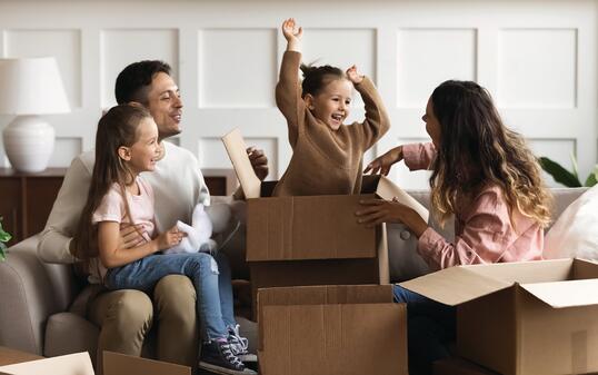 Happy parents and children playing on moving day unpacking boxes