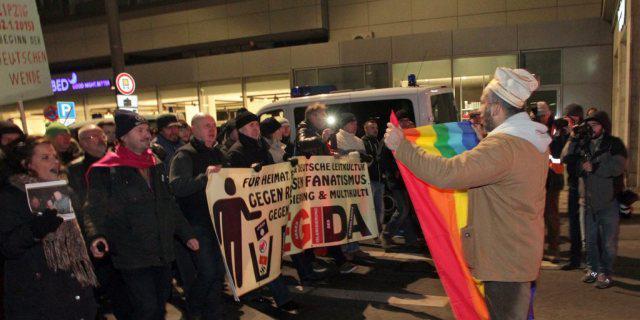 Mann mit Friedensfahne tritt in Leipzig dem Legida-Marsch entgegen Mann mit Friedensfahne tritt in Leipzig dem Legida-Marsch entgegen