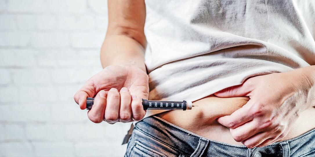 A woman injects insulin with insulin injection device into the subcutaneous tissue of abdomen