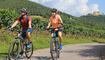 Young couple on a bicycle tour in the Palatinate near Maikammer. In the background vines and the Hambach Castle (Model released)