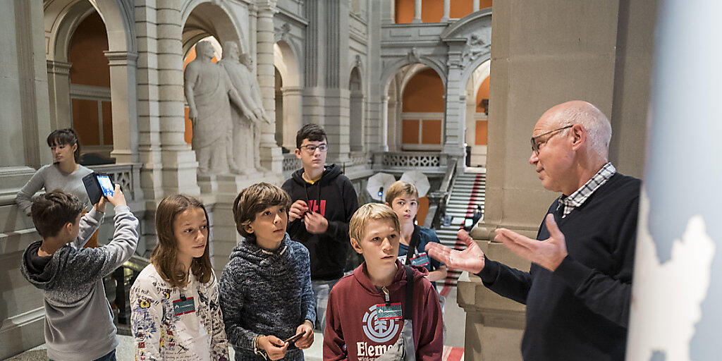 Andreas Blaser, Leiter &Ouml;ffentlichkeitsarbeit der Parlamentsdienste (rechts), f&uuml;hrt Kinder, die am Keystone-SDA-Zukunftstag teilnehmen, durch das Bundeshaus.