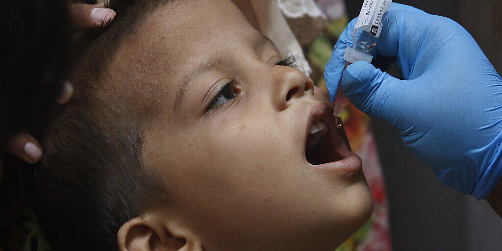 Ein Mitarbeiter des Gesundheitswesens verabreicht einem Kind einen Polio-Impfstoff. Nach Monaten der Unterbrechung durch die Corona-Pandemie hat in Pakistan erstmals wieder eine Impfkampagne gegen Kinderlähmung begonnen. Foto: Fareed Khan/AP/dpa
