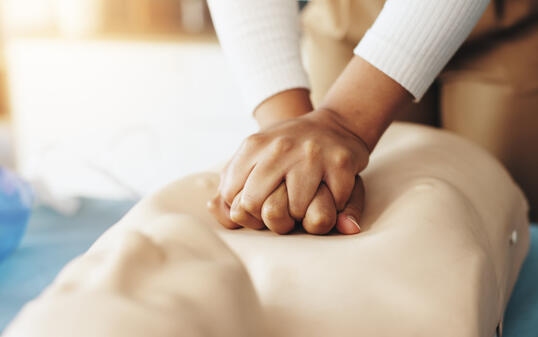 Hands, person and teaching cpr with dummy with demonstration, compression and breathing safety. Woman, mannequin and ventilation process for medical emergency, healthcare protocol and technique steps