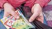 Swiss franc banknotes held in hands with black wallet