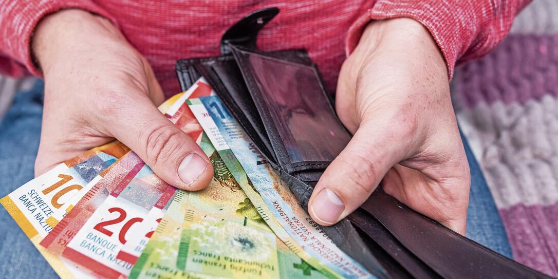 Swiss franc banknotes held in hands with black wallet