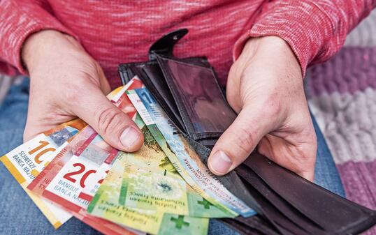Swiss franc banknotes held in hands with black wallet