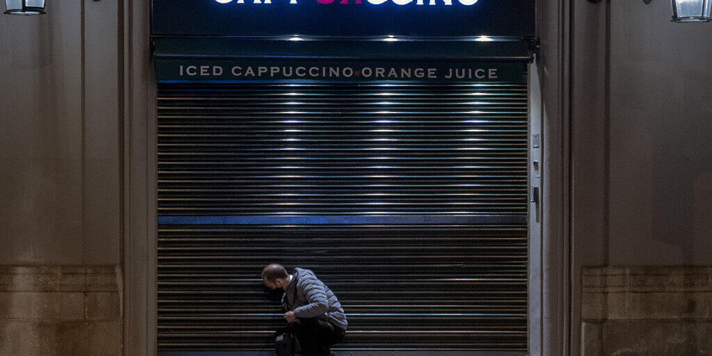 dpatopbilder - Ein Angestellter schließt ein Café vor der Sperrstunde in Barcelona. Foto: Emilio Morenatti/AP/dpa