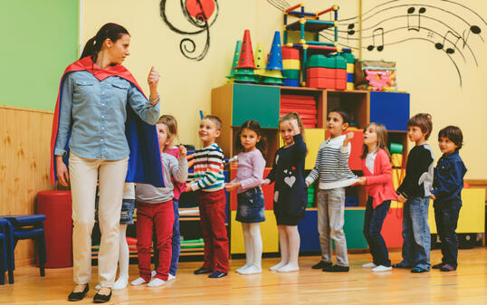 Group of children playing with their teacher in kindergarten