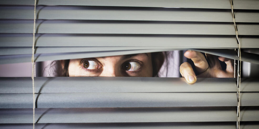 Brown-eyed girl peeps fearfully through venetian blinds Brown-eyed girl peeps fearfully through venetian blinds