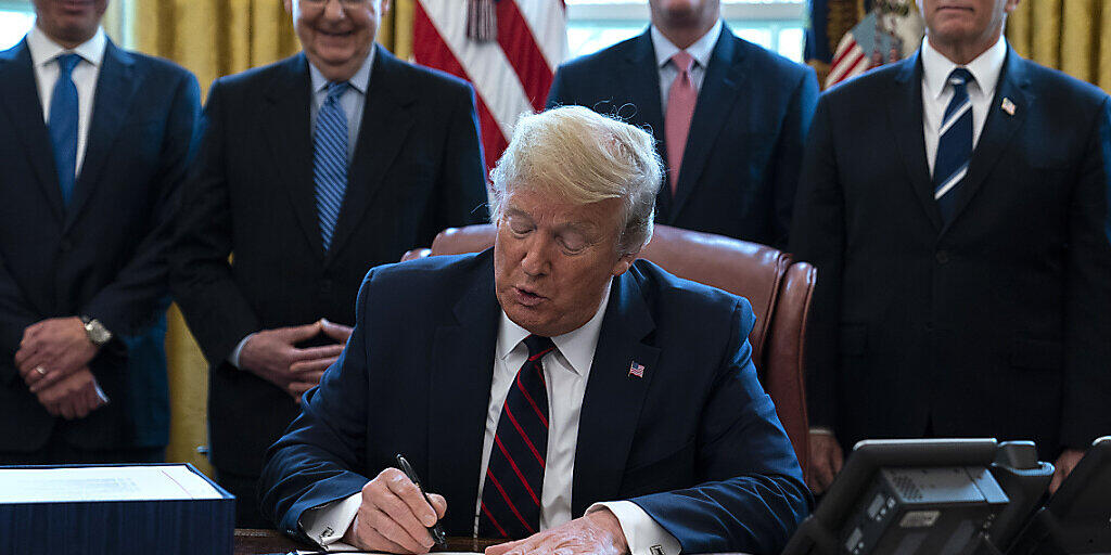 US-Präsident Donald Trump (Mitte) unterzeichnet im Oval Office des Weissen Hauses das Konjunkturpaket, mit dem rund 2 Billionen US-Dollar in die Wirtschaft gepumpt werden sollen.