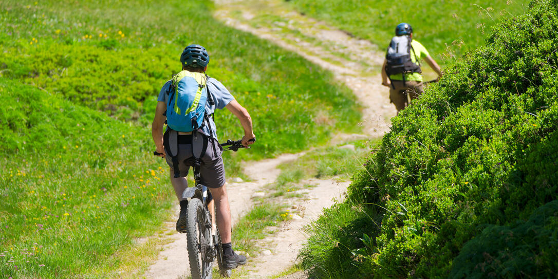 Rear view of mountain bikers on gravel road at Lauchernalp at L&Atilde;&para;tschental Valley in the Swiss Alps on a sunny late spring day.