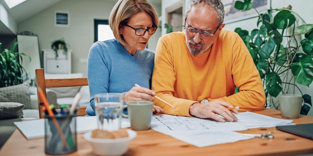 Senior couple sitting at table and looking into blueprints of their new home Senior couple sitting at table and looking into blueprints of their new home