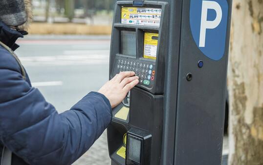 Man pays for parking the car using the parking machine