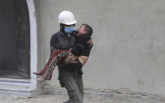 Ein Zivilschützer, ein sogenannter Weisshelm, trägt einen bei Angriffen der syrischen Armee verwundeten Knaben in Ost-Ghuta nahe Damaskus.
