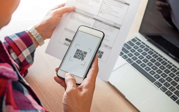 The butler is using a mobile phone to scan the QR code for the bill through the app. Convenient, fast, is an option of modern.