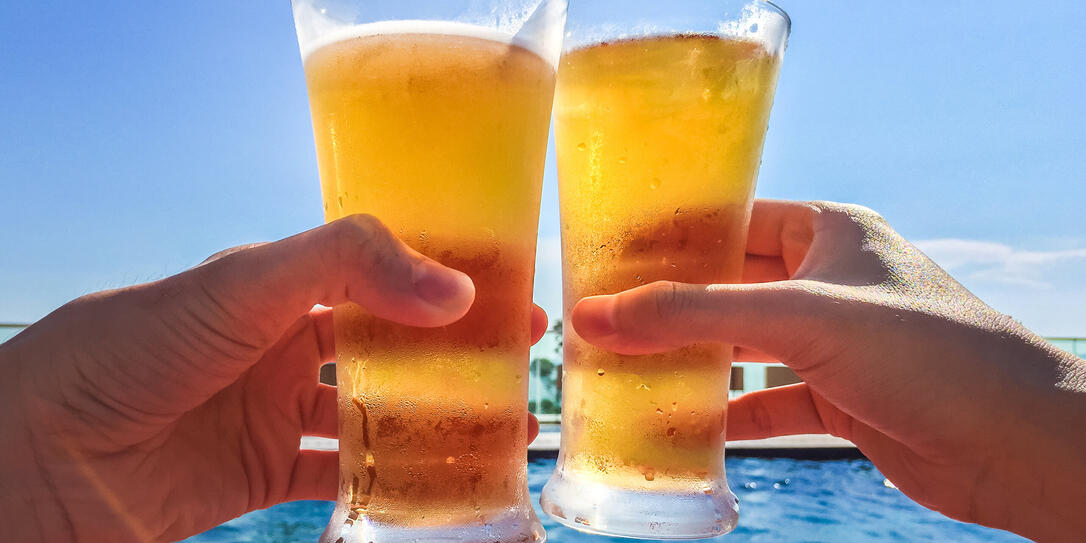 Hands Clinking Glasses of Beer by the pool