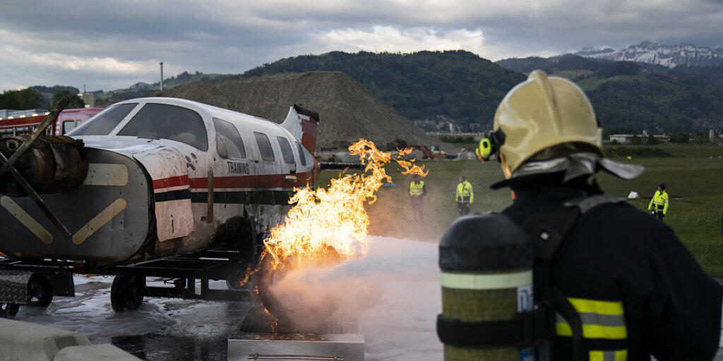 Ein Kleinflugzeug brennt, ein Feuerwehrmann greift ein: Notfallübung auf dem Flugplatz in Thun.