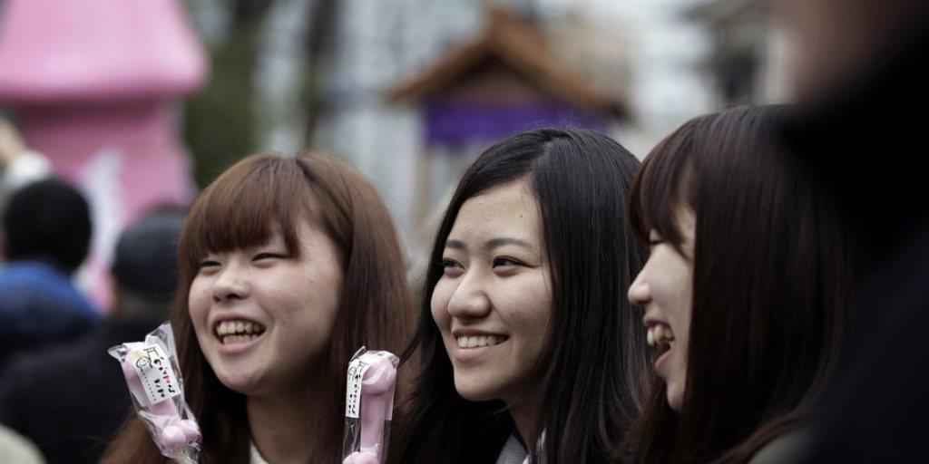 Frauen posieren beim alljährlichen Kanamara Matsuri mit phallusförmigen Süssigkeiten.