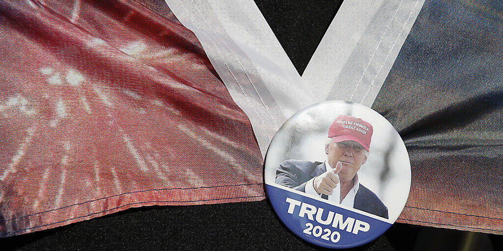 Eine Fraut trägt einen Button mit dem Bild des scheidenden US-Präsidenten Trump. Foto: Rebecca Blackwell/AP/dpa