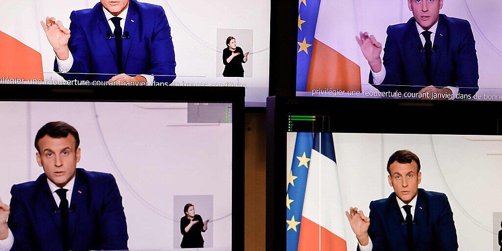 Die abfotografierten Bildschirme zeigen Emmanuel Macron, Präsident von Frankreich, der eine Fernsehansprache an die Nation zur aktuellen Corona-Lage hält. Angesichts einer verbesserten Corona-Lage hat Frankreichs Präsident Macron erste Lockerungen der strengen Beschränkungen im Land angekündigt. Foto: Thomas Coex/AFP/dpa - ACHTUNG: Nur zur redaktionellen Verwendung im Zusammenhang mit der aktuellen Berichterstattung und nur mit vollständiger Nennung des vorstehenden Credits