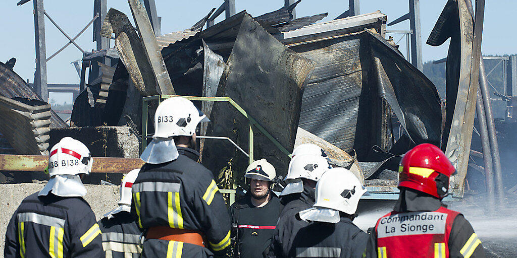 Feuerwehrleute überwachen am Donnerstag die Brandstätte auf dem Gelände der Sägerei Despond, die dem Freiburger SVP-Nationalrat Jean-François Rime gehört.