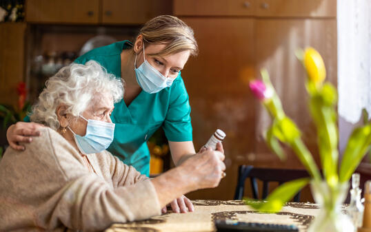 Home caregiver helping senior woman with medication