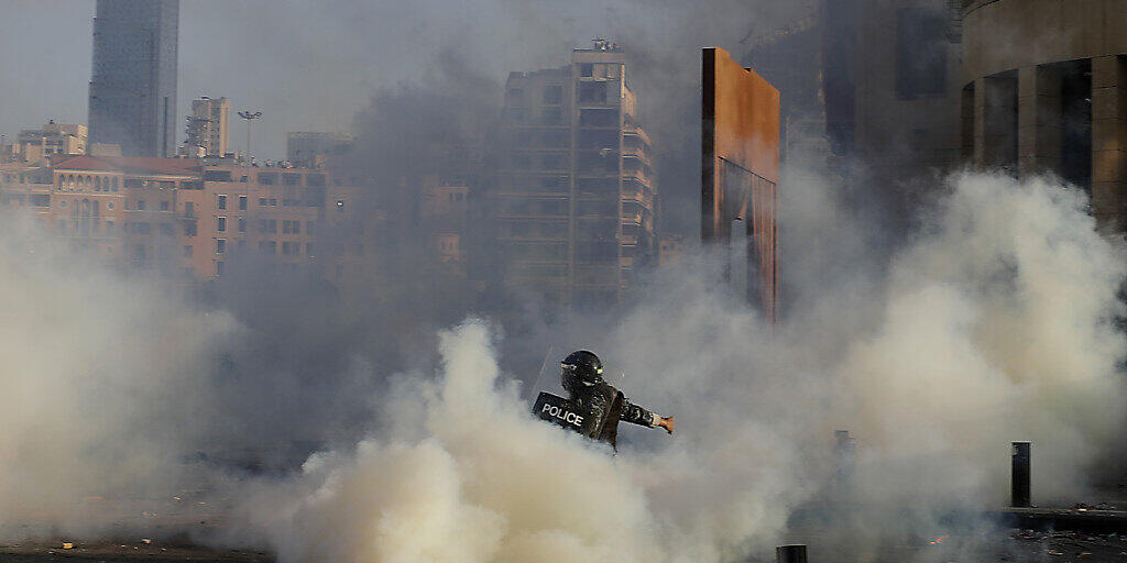 Ein Bereitschaftspolizist stößt bei einem Protest mit Demonstranten zusammen. Foto: Hassan Ammar/AP/dpa