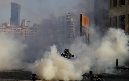 Ein Bereitschaftspolizist stößt bei einem Protest mit Demonstranten zusammen. Foto: Hassan Ammar/AP/dpa