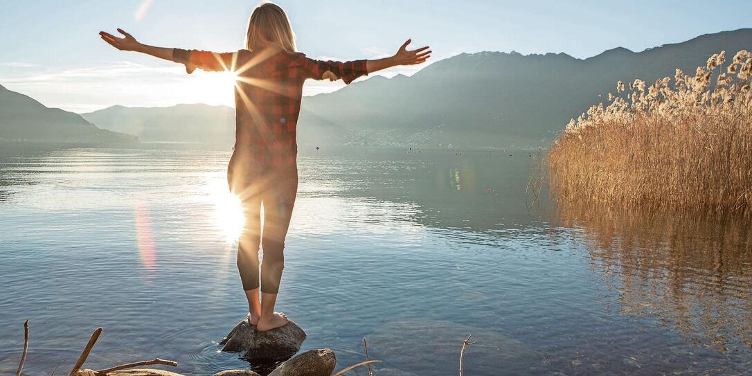 Young woman embracing nature, mountain lake