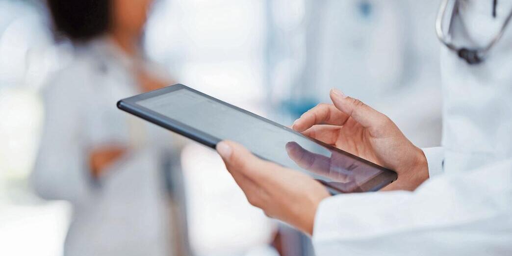 Medical, healthcare and insurance with a tablet in the hands of a doctor working in a hospital. Medicine, report and technology with a health professional at work in a clinic for care and wellness