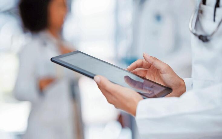 Medical, healthcare and insurance with a tablet in the hands of a doctor working in a hospital. Medicine, report and technology with a health professional at work in a clinic for care and wellness